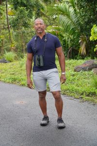 Christian Cooper stands with the forest as a backdrop