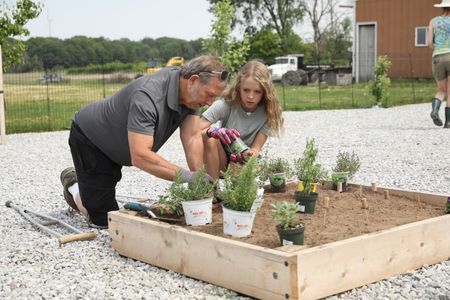 Art Reinhold and Brooklyn Reinhold plant vegetables in the Pol family farm's garden. (National Geographic)