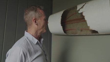 Nick Bester looking at the damage the shark caused to his surfski. (National Geographic/Robert Cowling)