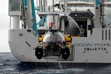Zoleka Filander, crew Buck Taylor and Edie Widder sit inside the submarine as it is lifted out of the water and hosed down by crew Lee Frey. (National Geographic/Mario Tadinac)