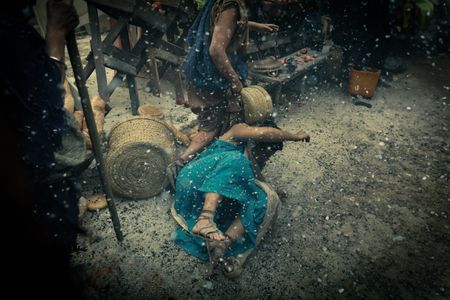 A woman falls to the ground amidst market stalls as she tries to escape Pompeii, while civilians run past her as volcanic ash rains from the sky. (National Geographic/Darrin Zammit Lupi)
