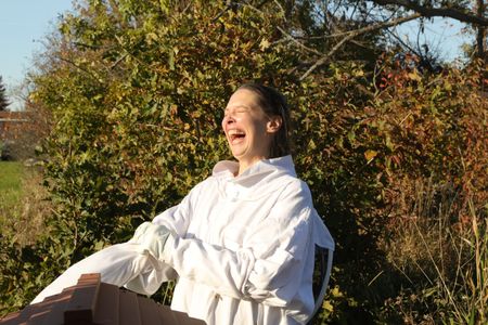 Beth Pol, in a bee suit, laughs while checking on the bees at the Pol family's farm to make sure they are ready for winter. (National Geographic)