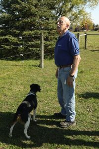 Dr. Pol stands with Dax, Ben Reinhold's dog, as he inspects the Pol family farm's fence line for repairs. (National Geographic)