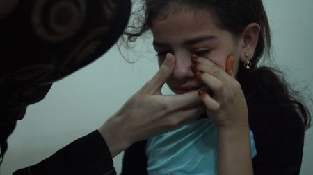 Al Ghouta, Syria - Dr Amani (L) comforts a little girl. (National Geographic)