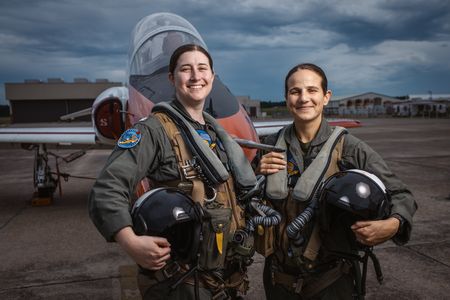 Students LT Carissa Meinster and Captain Steph Harris pose behind a T-45. (Credit: National Geographic/Freddie Claire)