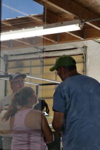Evan and Aurora Urwiler listen carefully to Dr. Ben Schroeder as he gives their goat a checkup. (National Geographic)