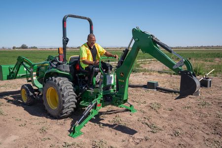 Christian Cooper operates a backhoe to dig a hole for an artificial burrow for the local burrowing owl population in Imperial Valley, CA. (National Geographic/Jon Kroll)