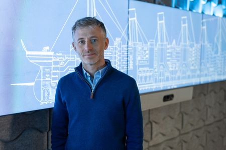 Simon Benson poses in front of blueprints of the Titanic. (National Geographic/Gary Moyes)
