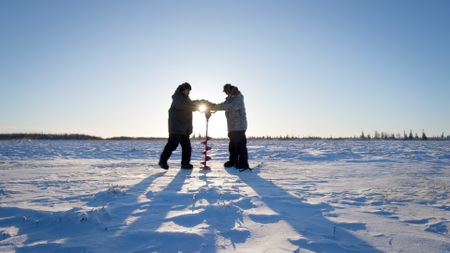 Gage and Avery Hoffman drill holes into the ice to fish. (BBC Studios/Danny Day)