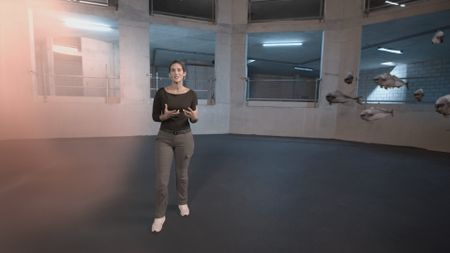 Dr. Diva Amon standing in the shark lab studio while a GFX school of fish swim by her and across the shot. (National Geographic)