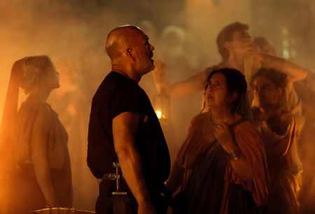 The Praetorian, played by Barry Aird, and Helvia, played by Christina Cole, look up in horror at the pyroclastic surge rushing towards the beach at Herculaneum, as citizens around them look to the Praetorian for assistance. (National Geographic/Darrin Zammit Lupi)