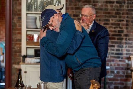 George Phoenix and Jan Demczur hug one another while John Paczkowski stands in background.(National Geographic/Virginia Sherwood)