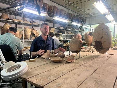 Ido Koch looks examines previously found artifacts at the Tel Aviv University, with students Yuval Amir, Sugi Freiman and Israa Shekh Yosef working in the background in Tel Aviv, Israel. (Windfall Films/Nava Mizrahi)