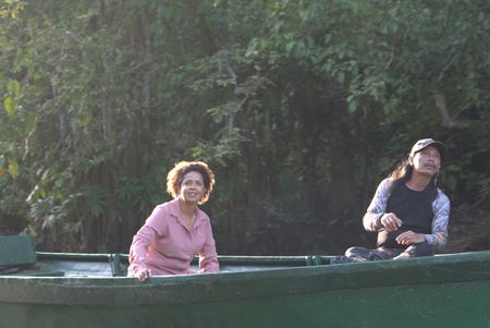 Paula Kahumbu and field researcher, Englebert Dausip, travel down the Kinabatangan River in hopes of catching sight of the pygmy elephants that live here. (National Geographic for Disney/Cede Prudente)