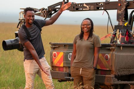 Anthony Njuguna and Faith Musembi stand next to the film vehicle rigged with the GSS camera, ready to set off in search of the pride. (National Geographic/Joe Treddenick)