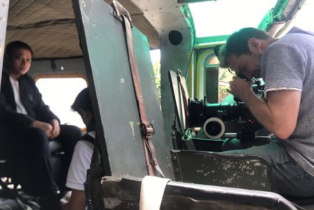 A BTS shot of a cameraman filming a reenactment of the hostages and negotiators traveling to the Myanmar/Thailand border via helicopter. (©2019 MCN International Pte Ltd. All Rights Reserved.)