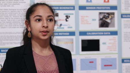 Close up of Anjali in front of her science fair project board. (National Geographic)