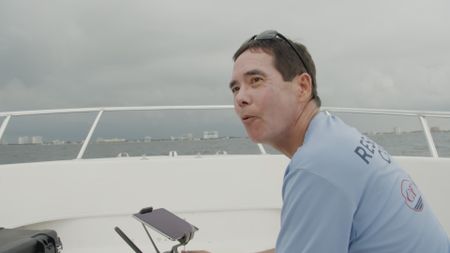 Dr. Stephen Kajuira on board a boat in Florida, operating a drone to analyze the sewage outfall within the area and connection to the rise in shark presence. (National Geographic)