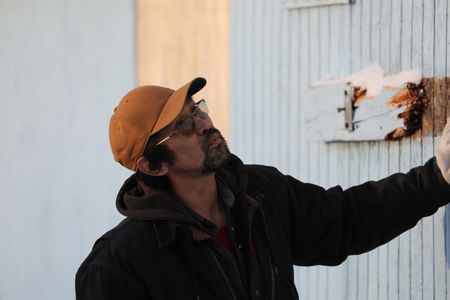 Marvin Agnot repairs the side of his home. (National Geographic/Lauren Bird Dixon)