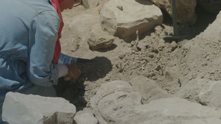 An unearthed stone head is revealed in the active citadel excavations in Amman, Jordan. (Windfall Films/Alex Collinge)