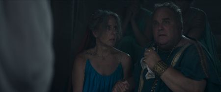 Cassius's wife, played by Jayne Giordanella, and Cassius, played by Robert Bowman, sit with the other guests in the gloom inside Julia Felix's house, as Cassius states that they will not evacuate. (National Geographic)