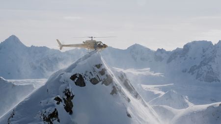 A helicopter lands on top of an Alaskan mountain and a skier hops off.  (mandatory credit:  Teton Gravity Research)