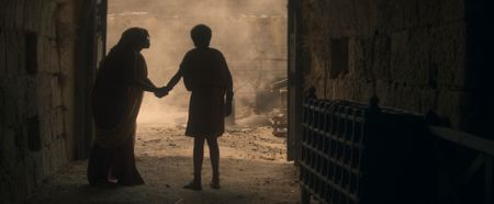 Aurelia Masuri, played by Angelina Chudi, clings to Avianius, played by Frankie Treadaway, in the doorway of the forge immediately after the first eruption of Vesuvius, pleading with him to be safe. (National Geographic)
