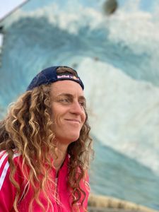 Big wave surfer Justine Dupont smiles in front of a mural that depicts a big wave.  (National Geographic/Gene Gallerano)