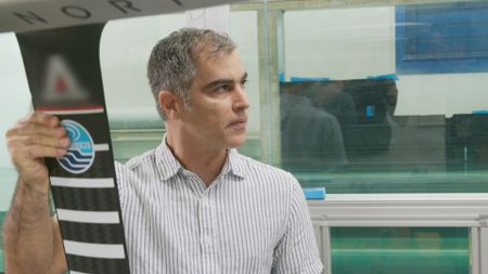 Professor Oscar M. Curet, expert, holding up a Hydrofoil wing while speaking to Dr. Yannis Papastamatiou, expert, in the Hydrodynamics lab at Florida Atlantic University. (National Geographic)