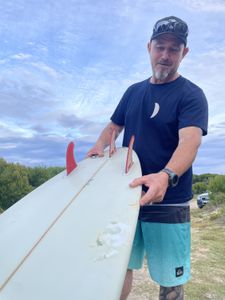 Stuart Anderson with his shark-bitten surfboard. (National Geographic/Robert Cowling)