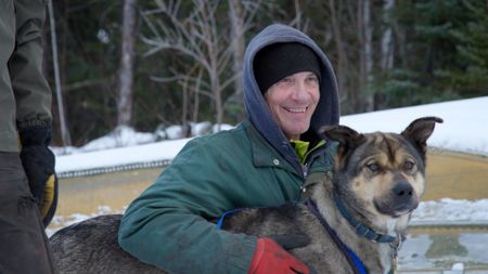 Andy Bassich congratulates his dogs after helping him get his boat out of the water and up the icy river bank. (BBC Studios/Ben Mullin)