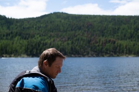 Kneeling by the river, professional kayaker Ben Stookesberry closes his eyes with the lake as his background.  (National Geographic/Harrison Gayton)