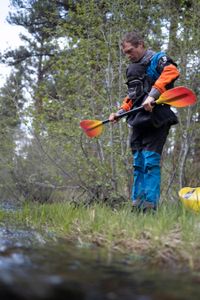 Professional kayaker Ben Stookesberry holds his paddle and looks down at it by the water.  (National Geographic/Harrison Gayton)
