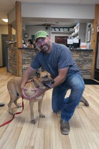 Dr. Ben Schroeder poses with Dublin, a Rhodesian ridgeback boxer mix, while holding a large shoulder mass that will be removed. (National Geographic)