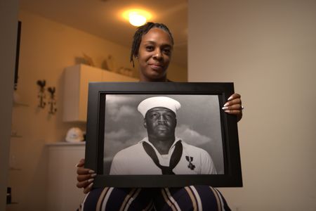 Desare' Allen holds a portrait of her great uncle Doris Miller at Flosetta Miller's home in Arlington, Texas. "Erased: WW2's Heroes of Color" tells the stories of three Black heroes who miraculously survived the attack on Pearl Harbor. One of these men, mess attendant Doris Miller, defied racial stereotypes when he shot down enemy planes during the attack. (National Geographic/Nelson Adeosun)