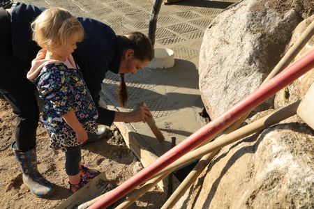 Beth Pol writes Abigail and Silas Pol's names in the wet concrete that will become the sheep hut's new flooring. (National Geographic)