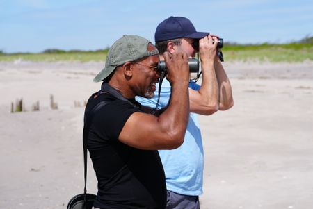 Christian Cooper and NYC Plover Project founder Chris Allieri look at a piping plover through binoculars at Fort Tilden. (National Geographic/Troy Christopher)