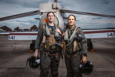 Students LT Carissa Meinster and Captain Steph Harris pose behind a T-45. (Credit: National Geographic/Freddie Claire)