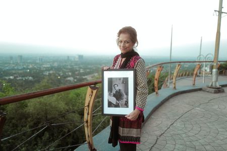 Zeenut Ziad holds a portrait of her father, Anis Khan, at her home in Islamabad, Pakistan. Captain Anis Ahmad Khan served courageously in Dunkirk and spent nearly four years as a prisoner of war – the longest of any Indian officer in WW2. (National Geographic/Daniel Dewsbury)