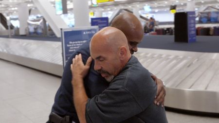 Chief Bowles gives Officer Bono a hug goodbye for his impending retirement from service, at the JFK International Airport, in New York. (National Geographic)