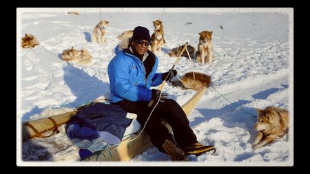 Dr. Alan Counter sitting on snow surrounded by dogs.  (courtesy of Philippa Counter)