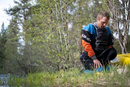 Professional kayaker Ben Stookesberry kneels by the river with his kayak and paddle.  (National Geographic/Harrison Gayton)
