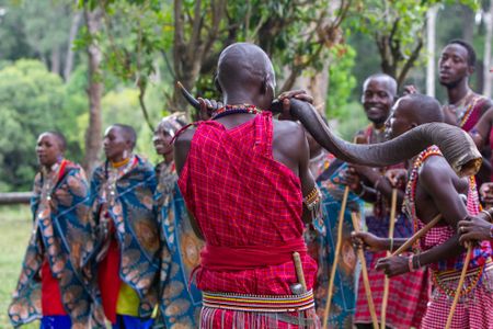 A group of Maasai sings a traditional song, while one member plays a tune on a kudu horn. (National Geographic/Jane Atkins)
