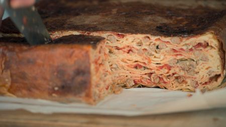 Timballo being cut, revealing the intricate layers of crespelle and meatballs inside.  (credit: National Geographic)