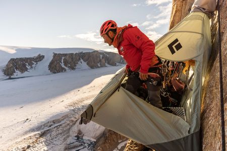 Adam Mike Kjeldsen looks down towards the ground, while standing in a portaledge on Pool Wall, in Eastern Greenland.  (photo credit: National Geographic/Pablo Durana)
