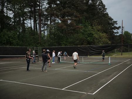 Sound recordist Phil Bax, DOP Jon Southgate-Sayers, Director Lana Salah, and camera Charlie Laing, filming Student Captain Steph Harris playing tennis with fellow students LTJG Dylan Horan and LTJG Spenser Neel. (National Geographic/Lyndsi Gutierrez)