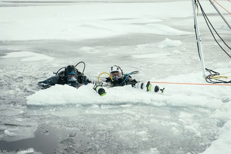 Will Smith, left, and Polar Ecologist Dr. Allison Fong dive under the ice in the North Pole to collect samples. (credit: National Geographic/Freddie Claire)