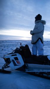 Agnes Hailstone glasses for caribou on top of her snowmobile. (BBC Studios Reality Productions, LLC/Ashton Hurlburt)