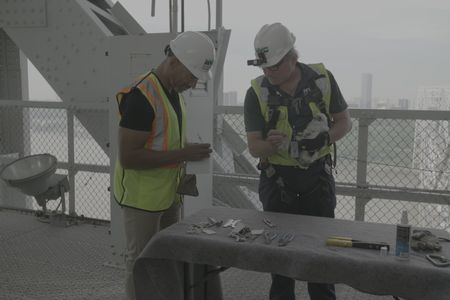 Christian Cooper writes down measurements as Chris Nadareski, Research Scientist and Section Chief of the Wildlife Studies Program for the NYCDEP, holds a baby peregrine falcon on the George Washington Bridge. (National Geographic/Grayson Horan)