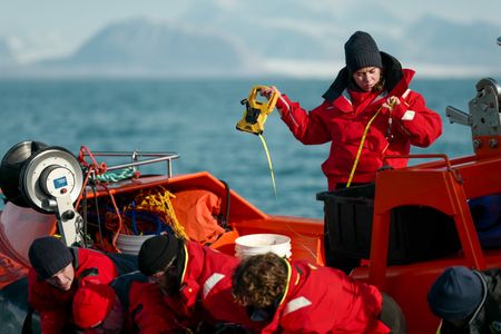 Melissa Marquez looks at a measuring tape as others work to tag a shark. (National Geographic/Mario Tadinac)